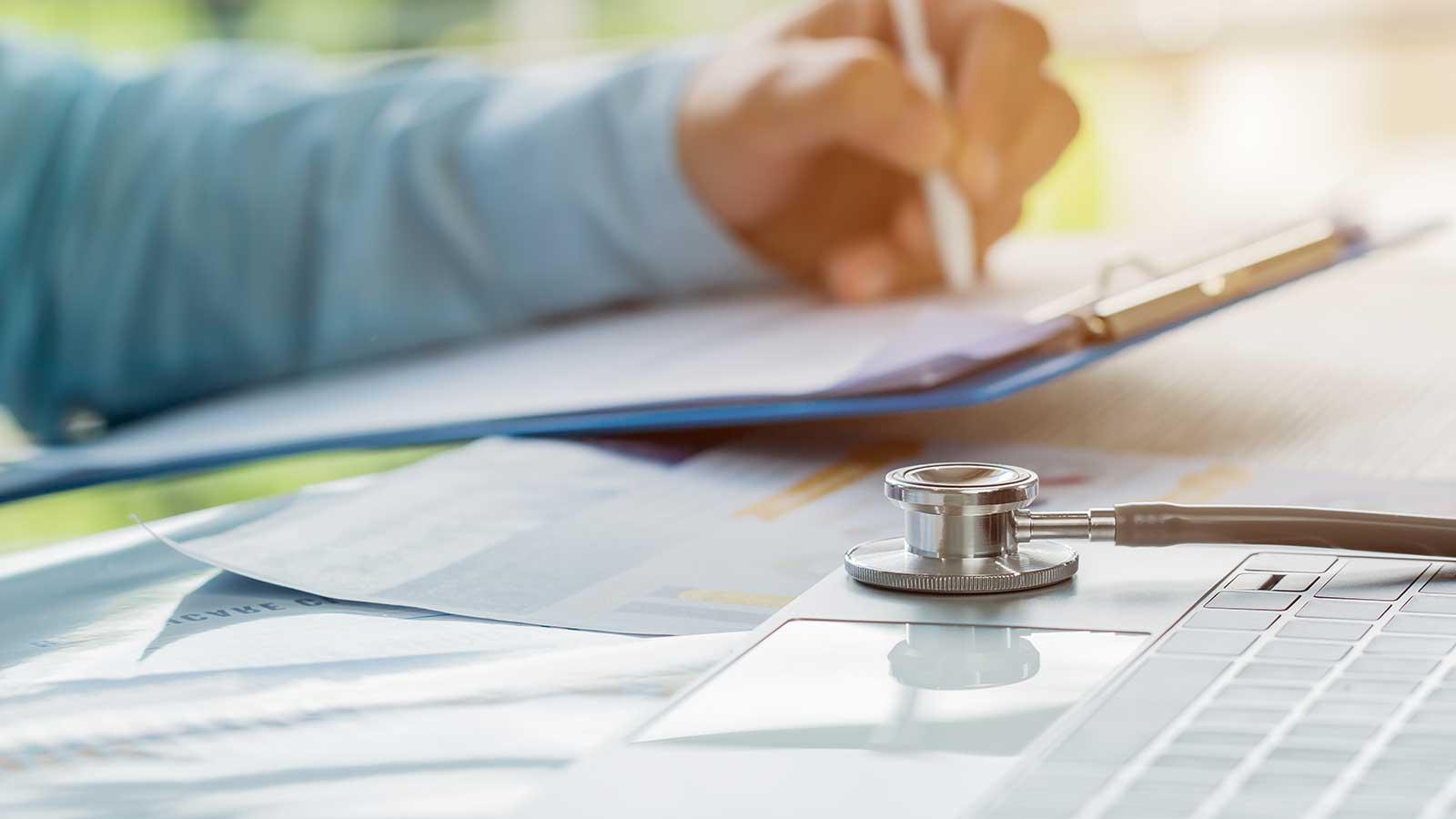 Stethoscope in desk with hands in background